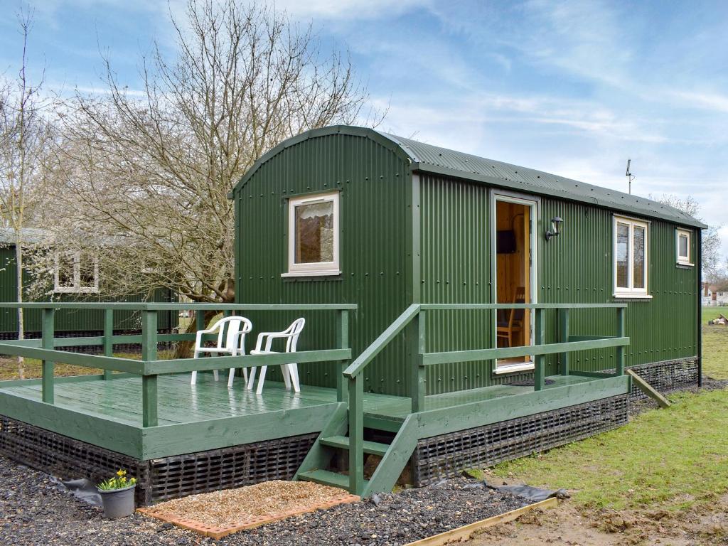 una casita verde con terraza verde en Shepherds Hut 2 At Laddingford - Uk32534 en Yalding