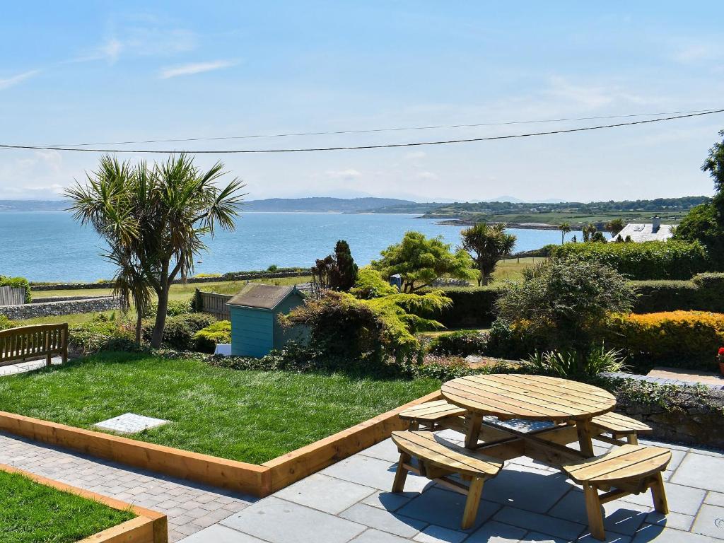 a picnic table on a patio with a view of the ocean at Bryn Awel in Moelfre