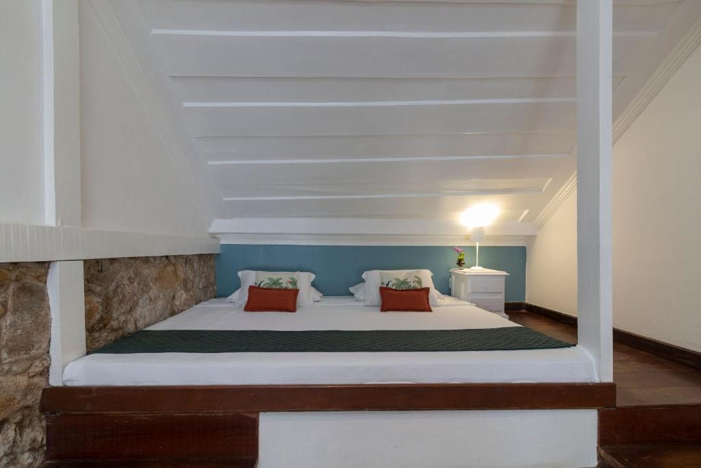 een slaapkamer met een wit bed met 2 kussens bij Sandi Hotel in Paraty