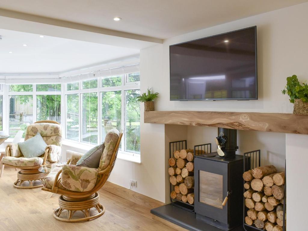 a living room with a fireplace and a flat screen tv at Tan Yr Ardd Bach in Llanwnda