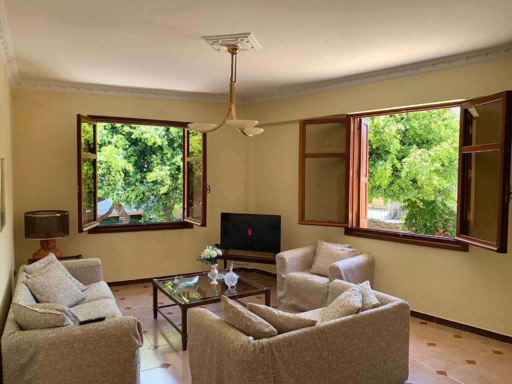 a living room with two chairs and a table and two windows at The Knights Courtyard in Rhodes Town