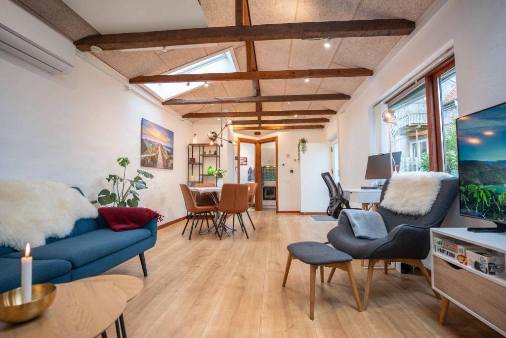 ein Wohnzimmer mit einem blauen Sofa und Stühlen in der Unterkunft New Cozy Central Scandinavian Skylight House in Horsens
