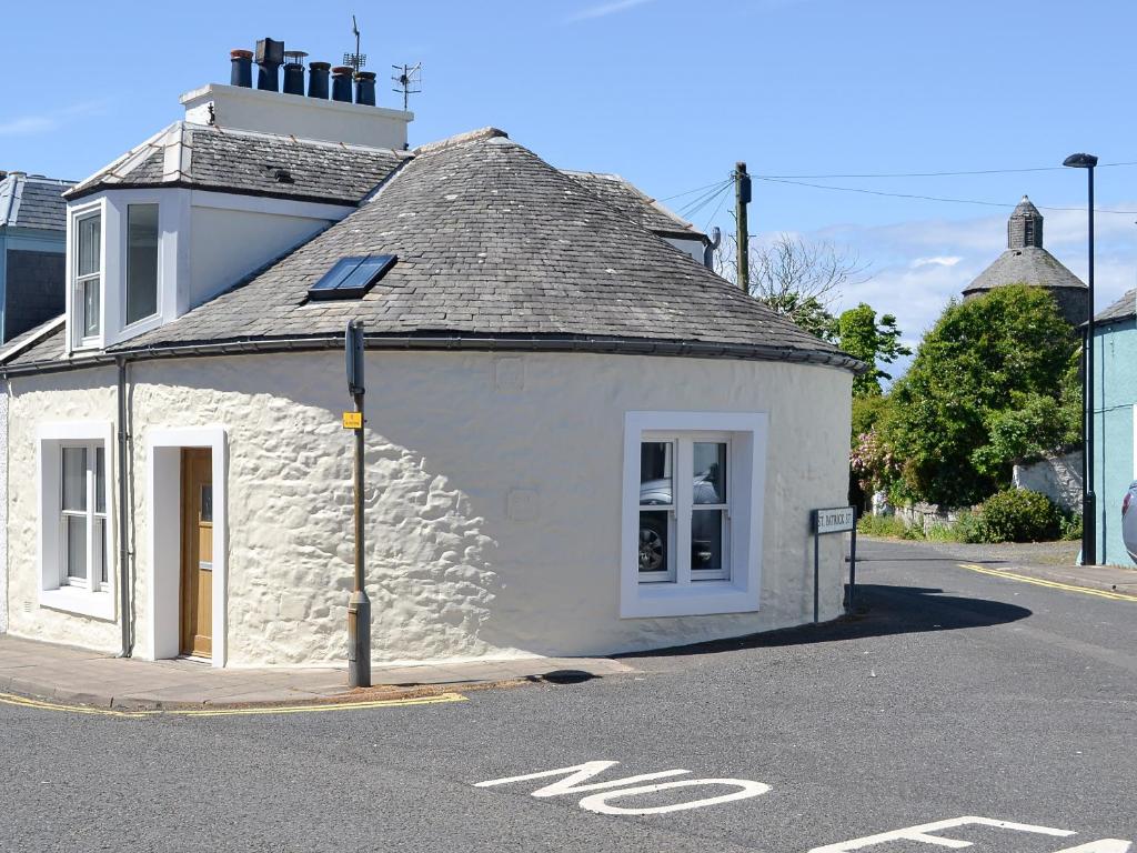 un piccolo edificio bianco sul lato di una strada di The Old Toll House a Portpatrick