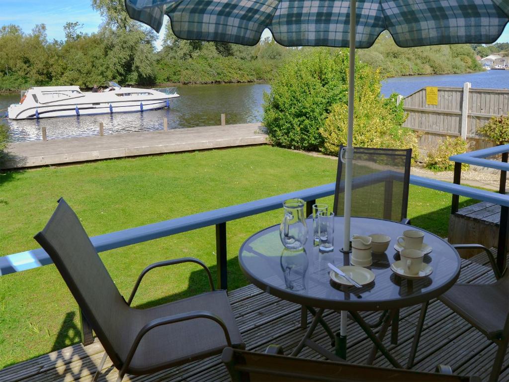 a table and chairs on a deck with an umbrella at Silver Bream in Brundall