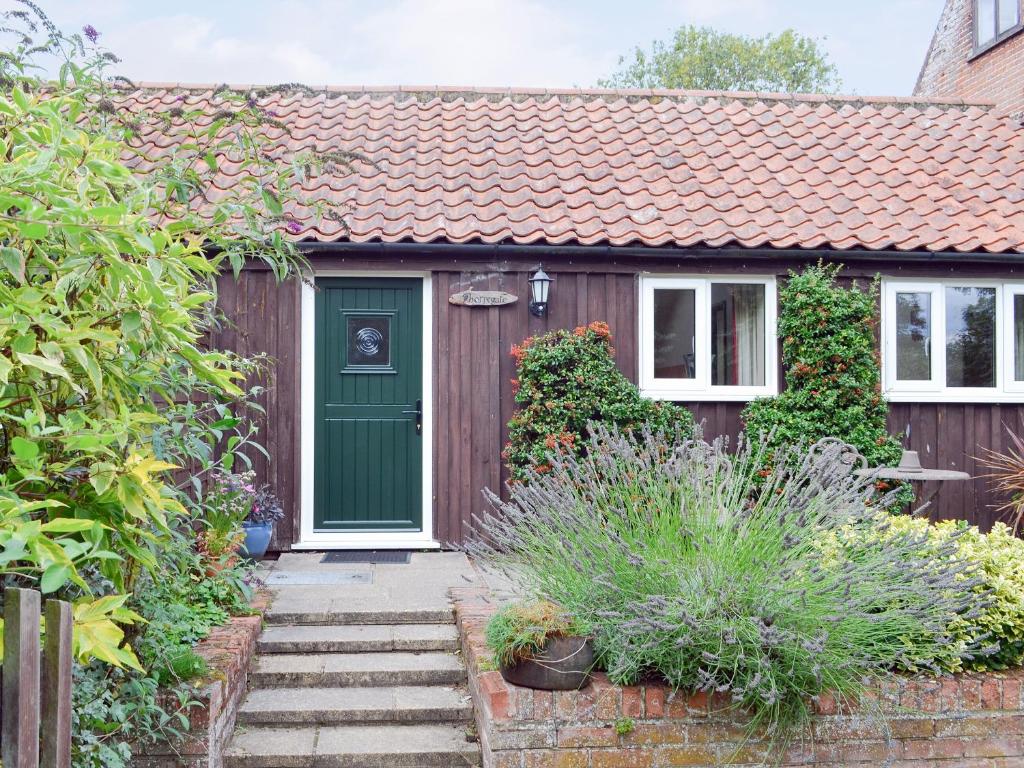 a small house with a green door and stairs at Thorpegate - E3076 in Thorpe Market