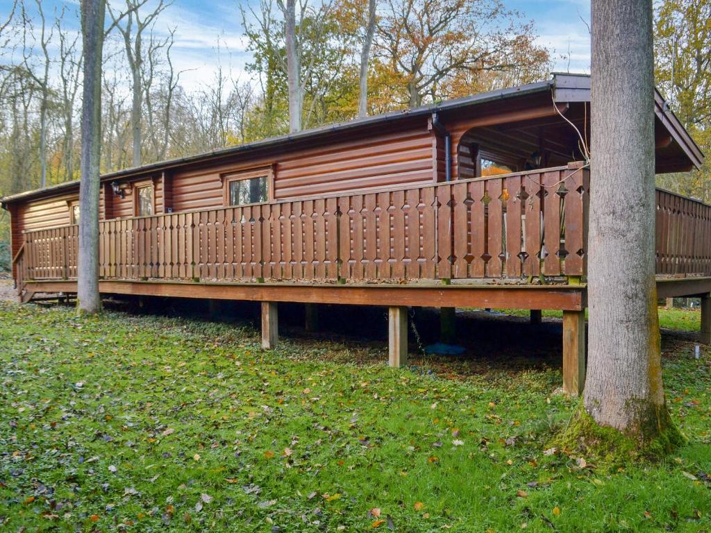 a wooden cabin with a wooden deck next to a tree at Holme Garth Lodge in Legbourne