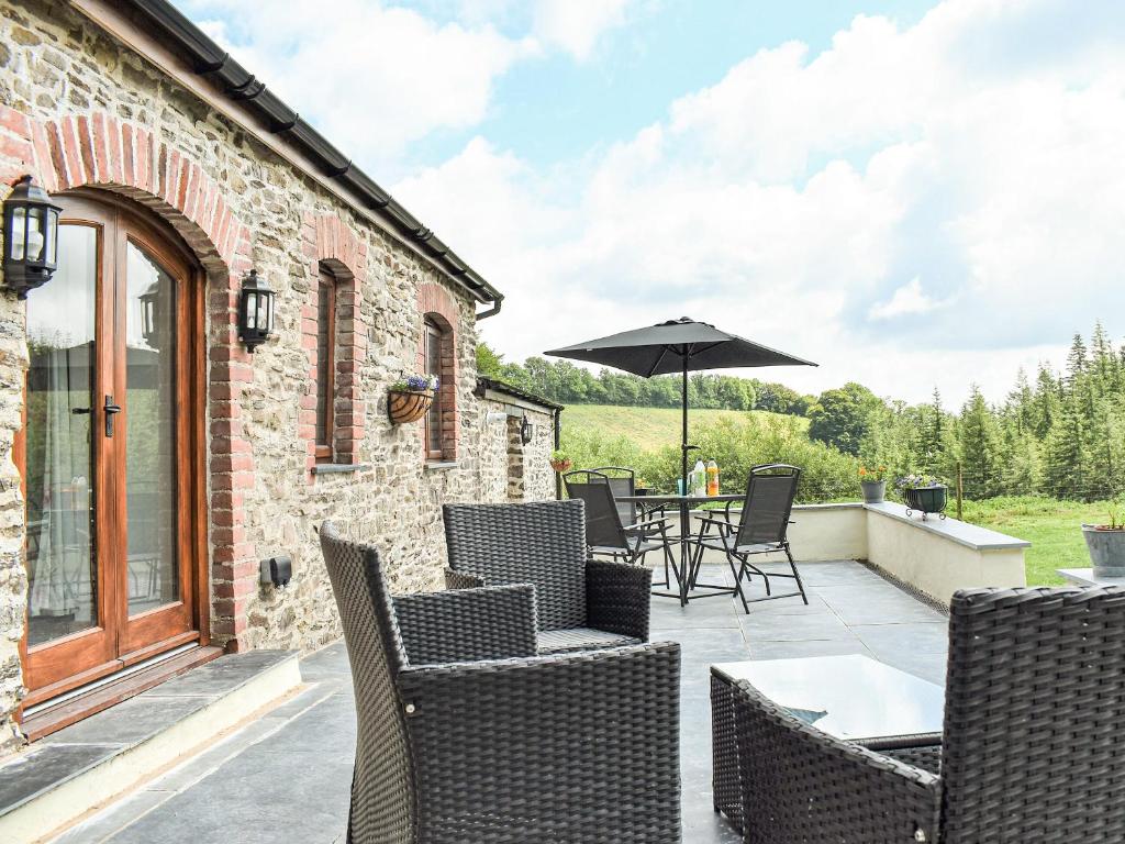 un patio con mesa, sillas y sombrilla en Slade Cottage - Uk35027, en Highbray