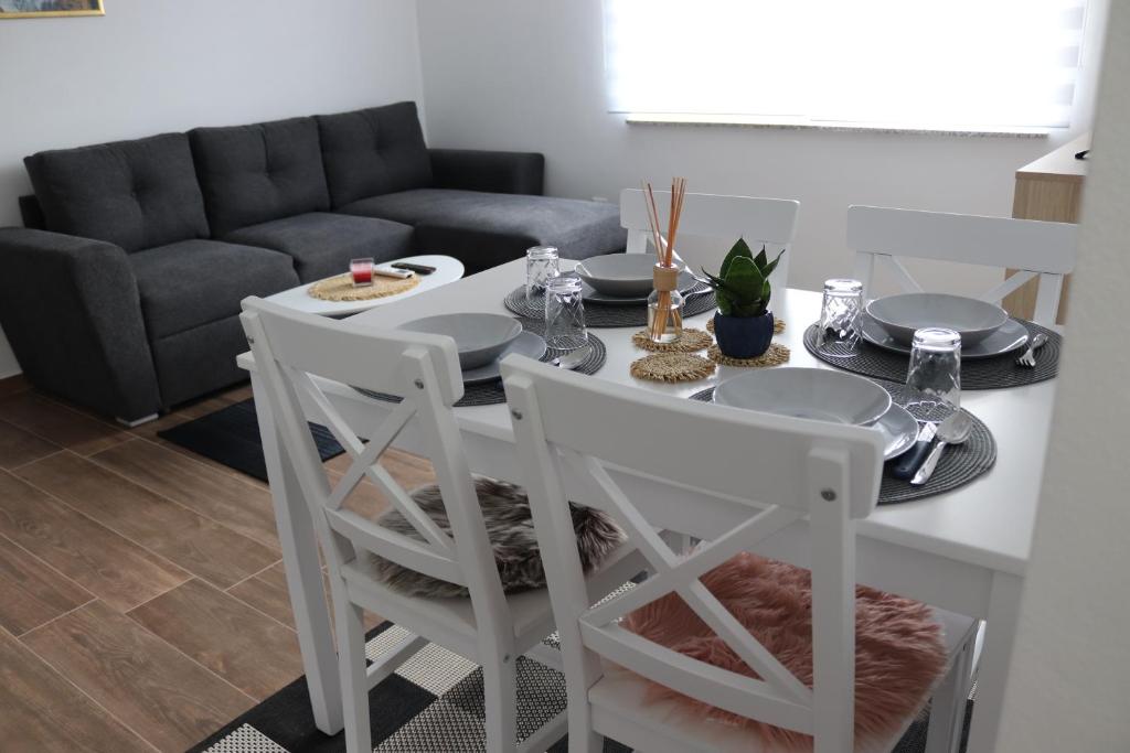 a white dining room table with chairs and a couch at Apartman ŠafraM in Ðurmanec