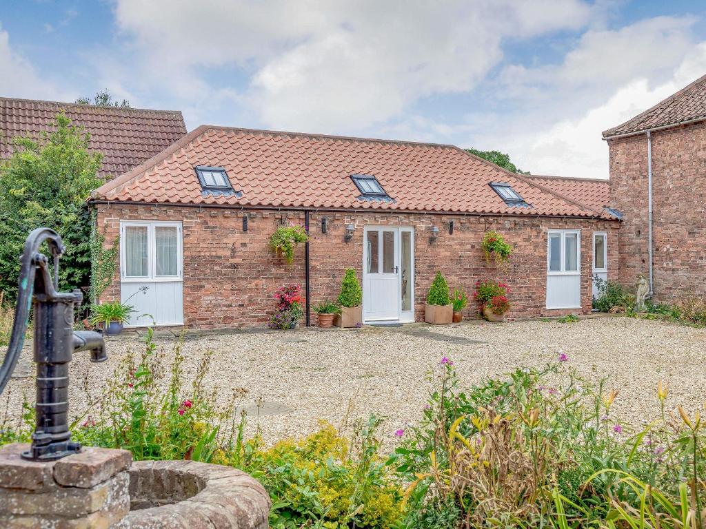 a brick house with white doors and a courtyard at The Stables in Laneham