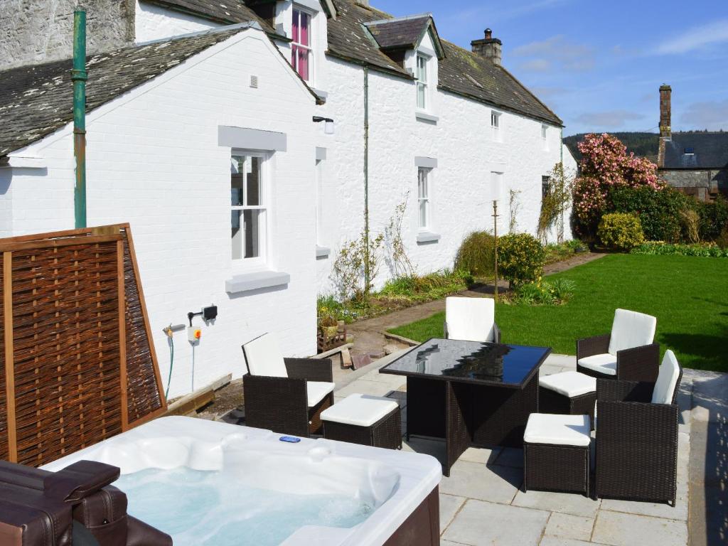 a backyard with a hot tub and chairs and a house at The Dairy House in Creebridge