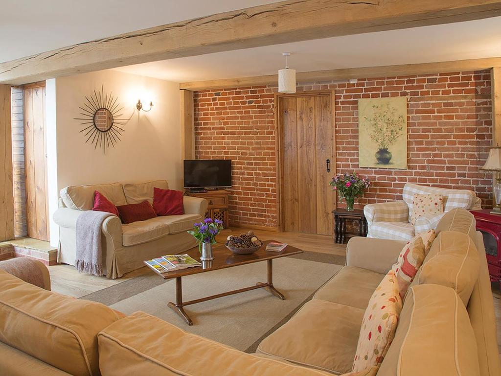 a living room with a couch and a brick wall at Old Corn Mill - Ukc3170 in Walpole