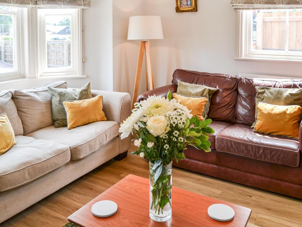 a living room with a couch and a vase of flowers at 1 Alexandra Villa in Coltishall