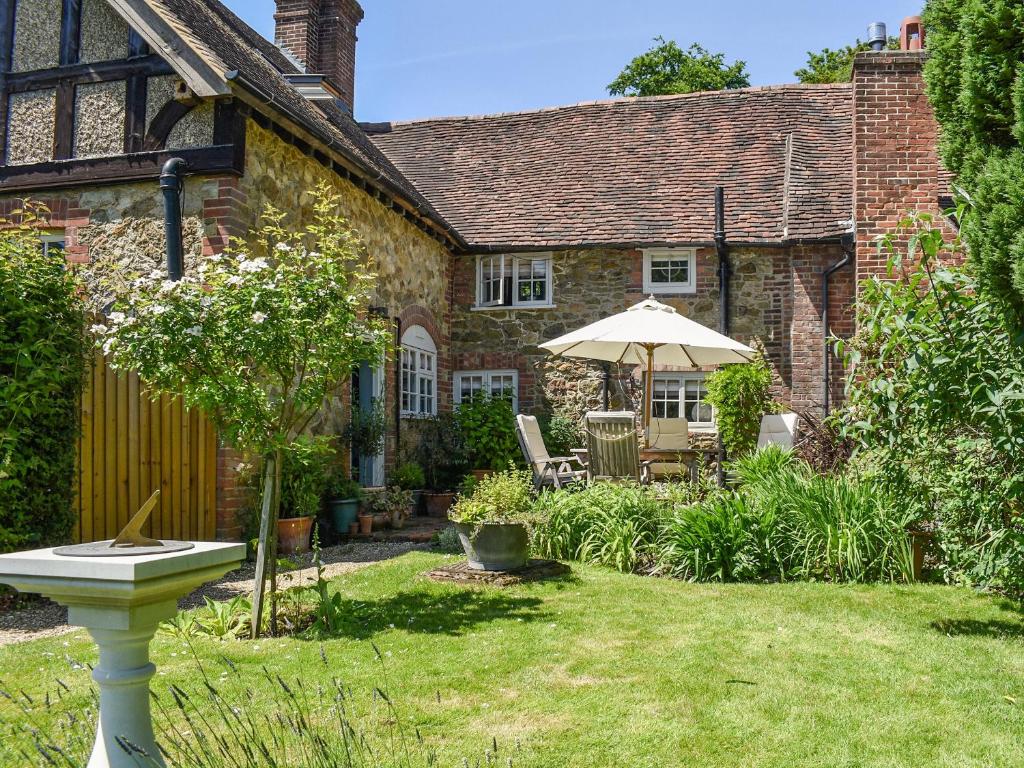 a garden with an umbrella and a house at Chapel Cottage, in Holmbury Saint Mary