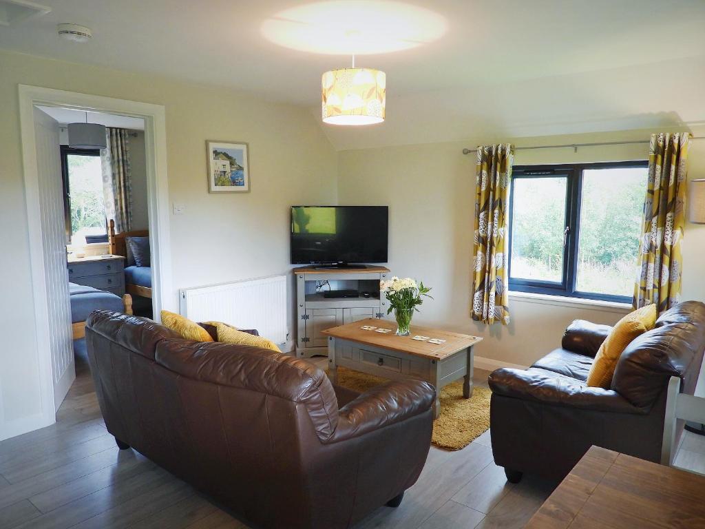 a living room with two leather couches and a tv at Foxglove Lodge - Uk13448 in Halwill