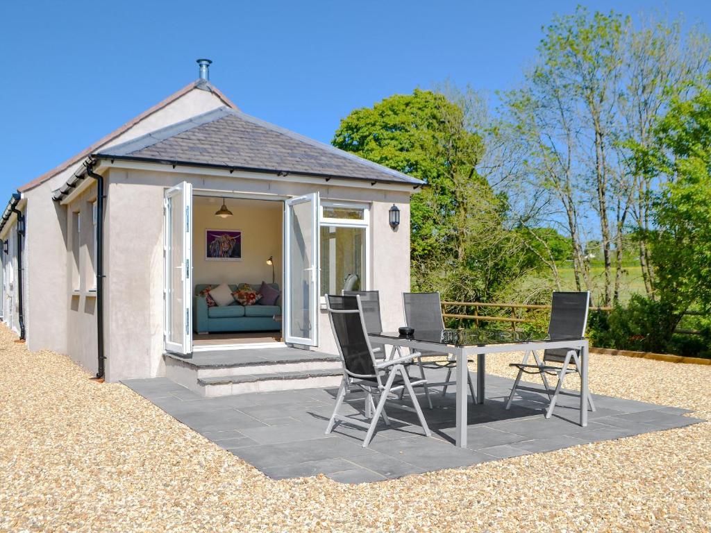 a patio with a table and chairs in front of a house at Riverside Cottage in Boreland