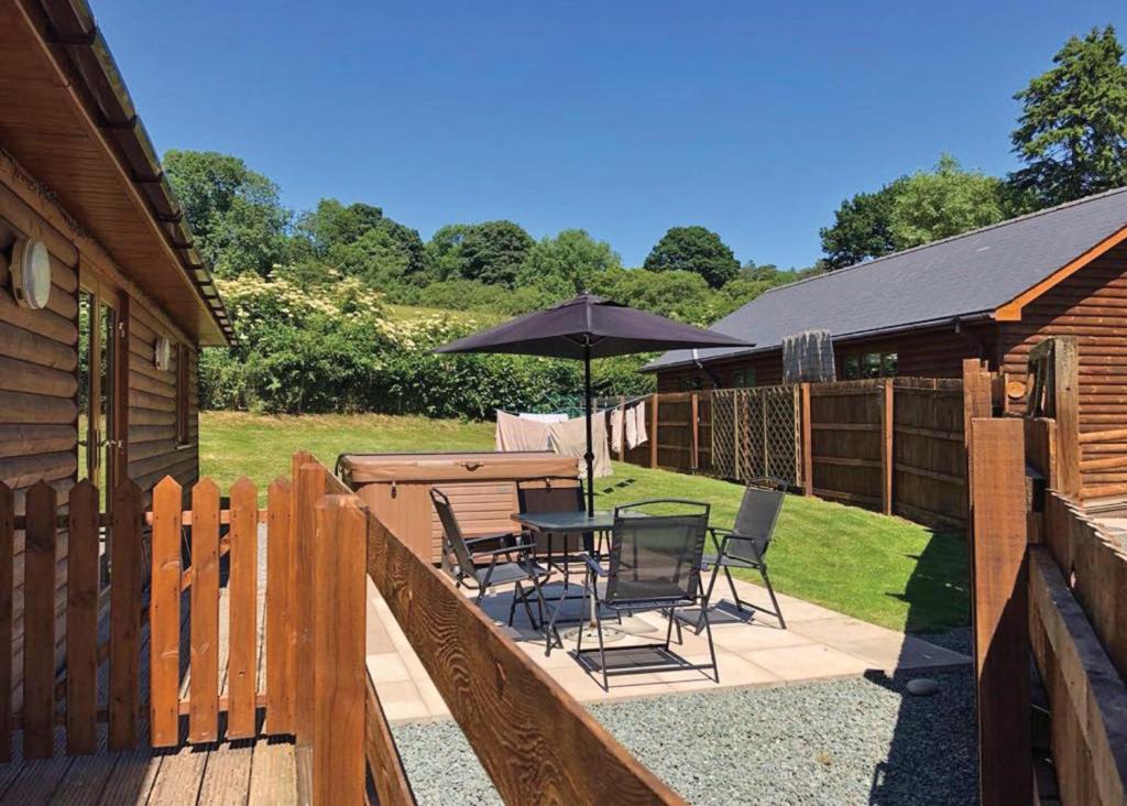 a patio with a table and chairs and an umbrella at Heartsease Lodges in Llanddewi Ystradenny