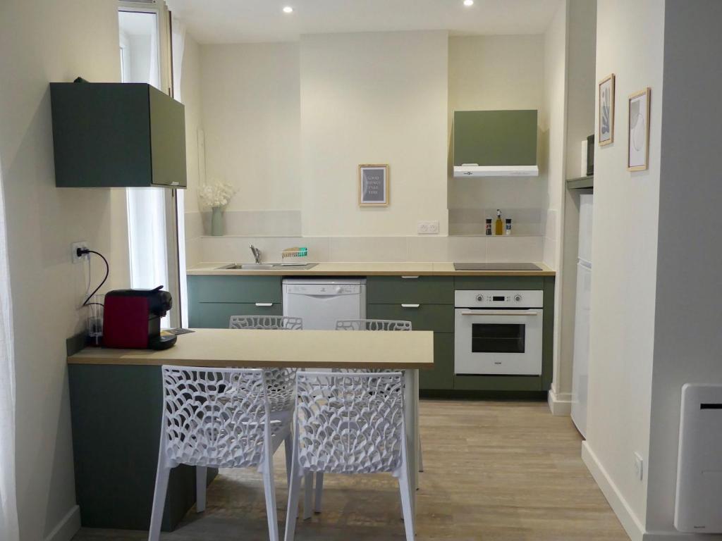 a kitchen with green cabinets and a table and chairs at « Le Michelet »un cocon en ville in Saint-Étienne