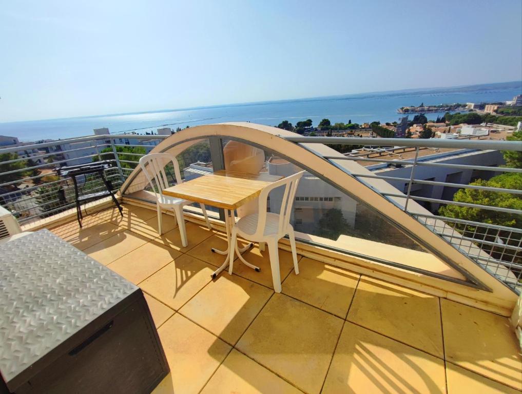 a balcony with a table and a view of the ocean at T2 vue panoramique, piscine, parking, wifi, 2 tv connectées, netflix, clim, ascenseur, salon de jardin teck, barbecue in Sète