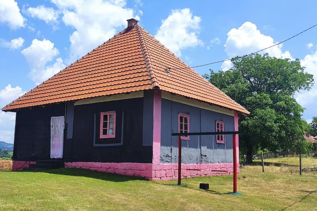 une petite maison noire et rose avec un toit dans l'établissement Šeherezada, à Kosjeric