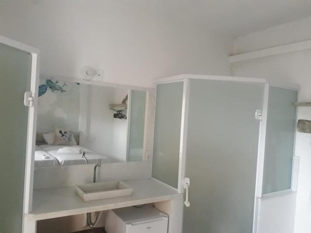 a white bathroom with a sink and a mirror at Pousada Atracadouro Boipeba in Cayru