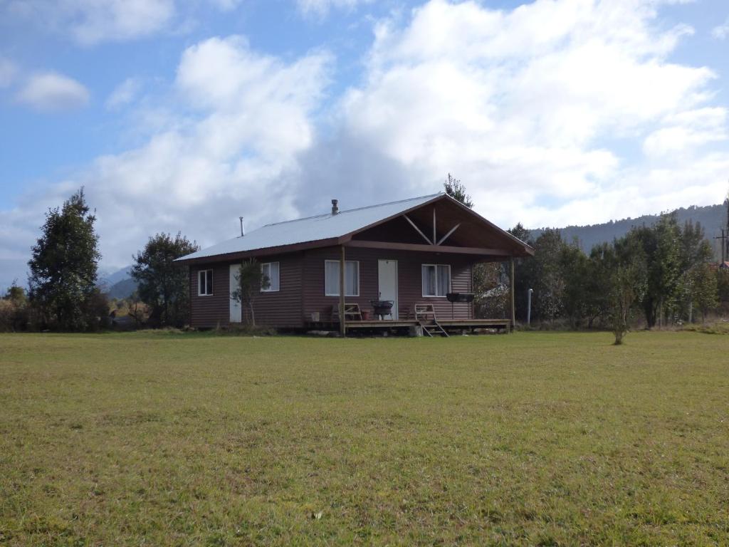 a house in a field with a large field at Cabañas Austral Rivers in Puelo