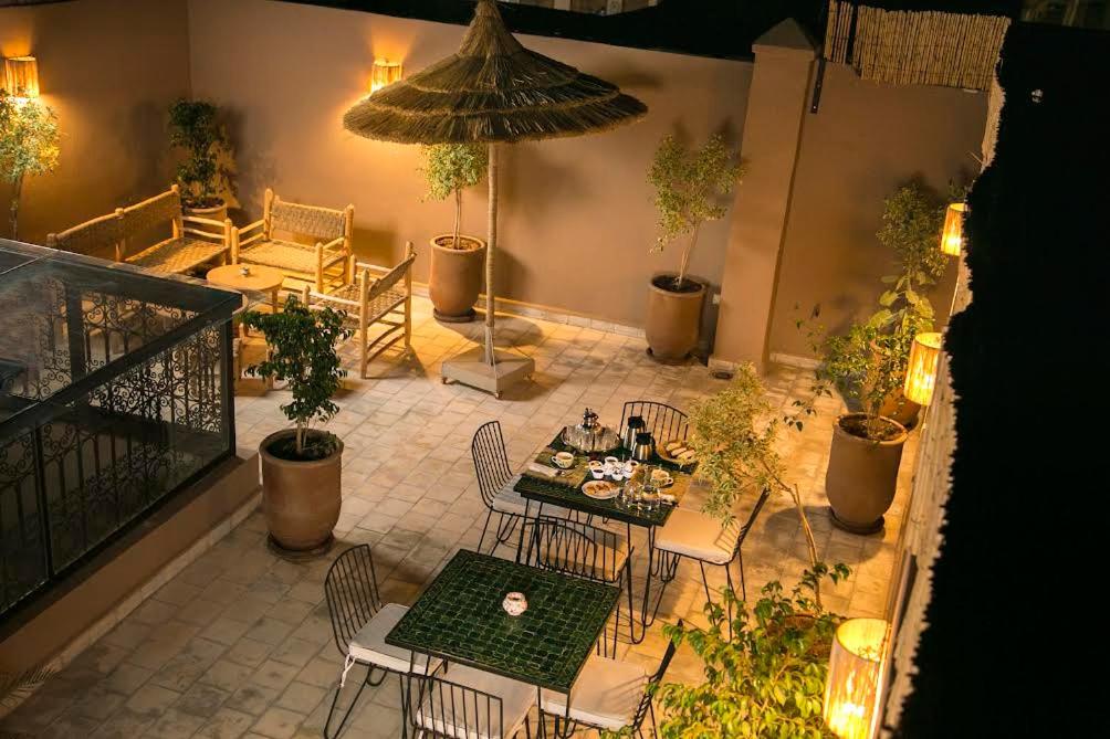 um pátio com uma mesa, cadeiras e um guarda-sol em Riad Sabria em Marrakech