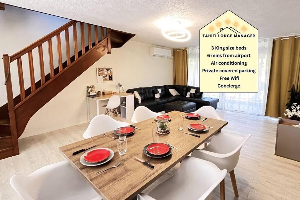 uma sala de jantar com uma mesa de madeira e cadeiras brancas em HEIPOE LODGE - 6 min airport, Wifi, AC & Parking em Papeete