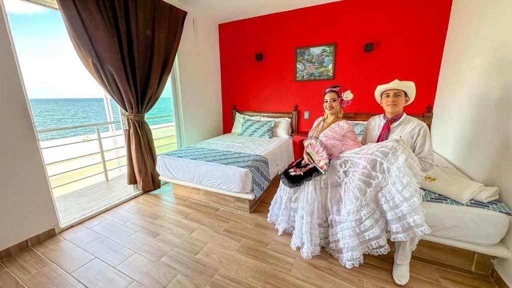 un hombre y una mujer sentados en una habitación con una pared roja en Hotel Jar8 Bule en Boca del Río
