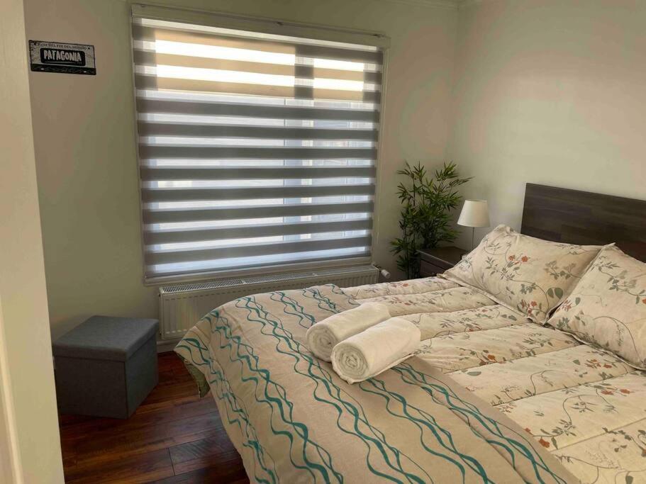 Dormitorio con cama con ventana y almohada en Departamento manantiales, en Punta Arenas