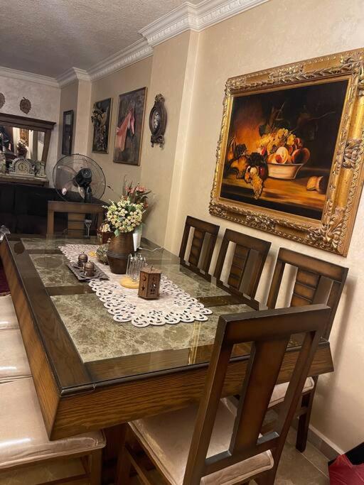 einen Esstisch mit Stühlen und ein Gemälde an der Wand in der Unterkunft 3 bedroom apartment in Ţāb Kirā‘
