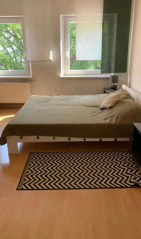 uma cama num quarto com um tapete e duas janelas em Großzügiges Zimmer in Burgnähe em Nurembergue