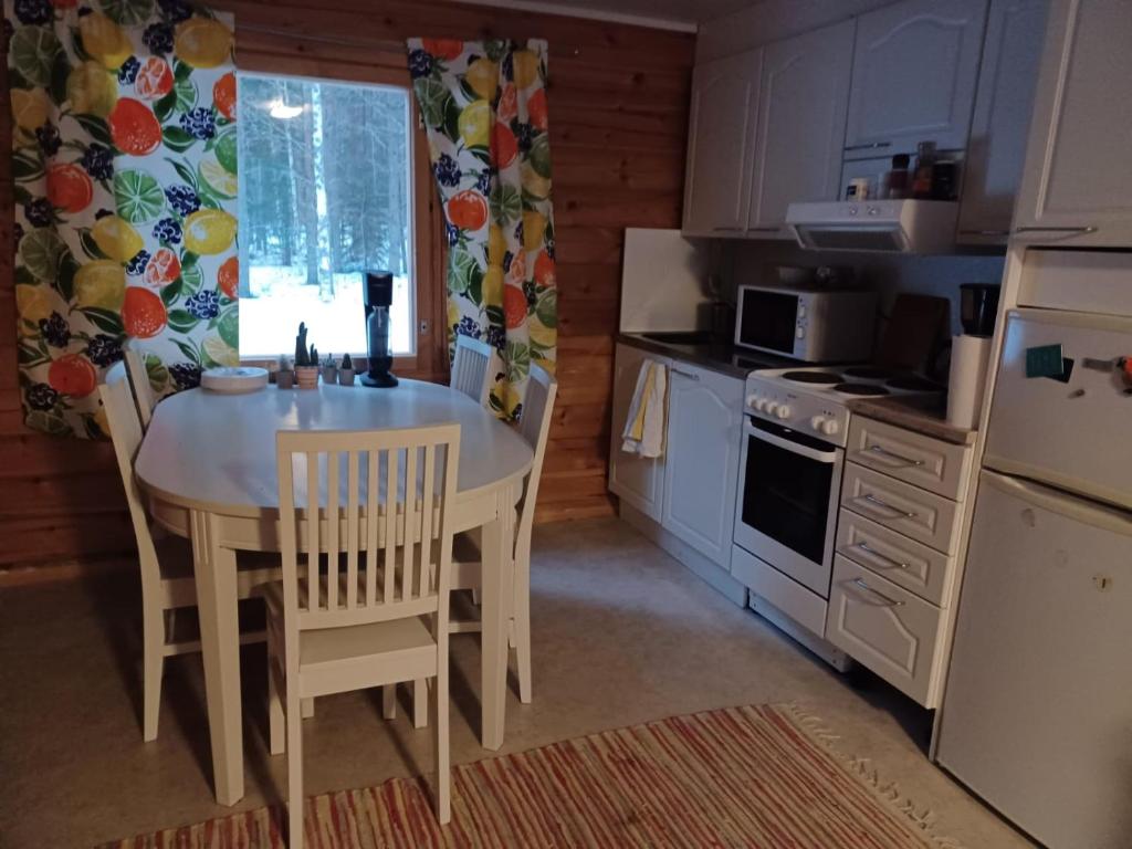 y cocina con mesa blanca, sillas y fogones. en Jamali Cabin, en Lieksa
