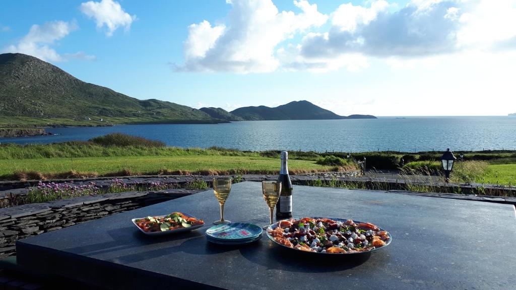 a table with two plates of food and a glass of wine at Fuchsia Lodge - New Luxury 5* Beachside Lodge with Sauna - 4 beds ensuite - Spectacular Location in Cahersiveen