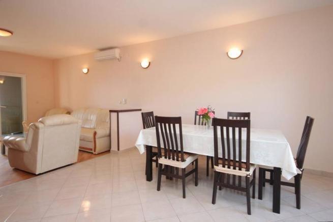 a dining room with a table and chairs and a bedroom at Apartments Pašman in Banj