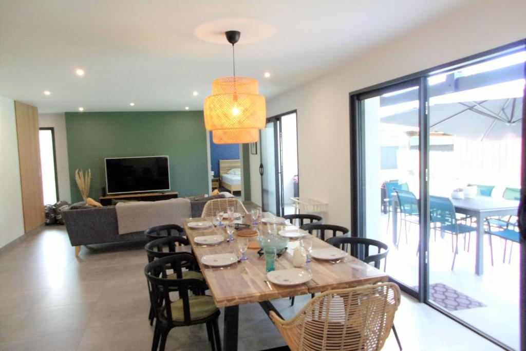 a dining room and living room with a table and chairs at Spacious house with garden in Soustons