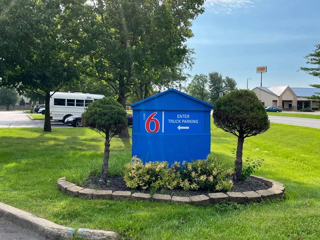 a blue sign in the grass with two trees at Motel 6-Lafayette, IN in Lafayette