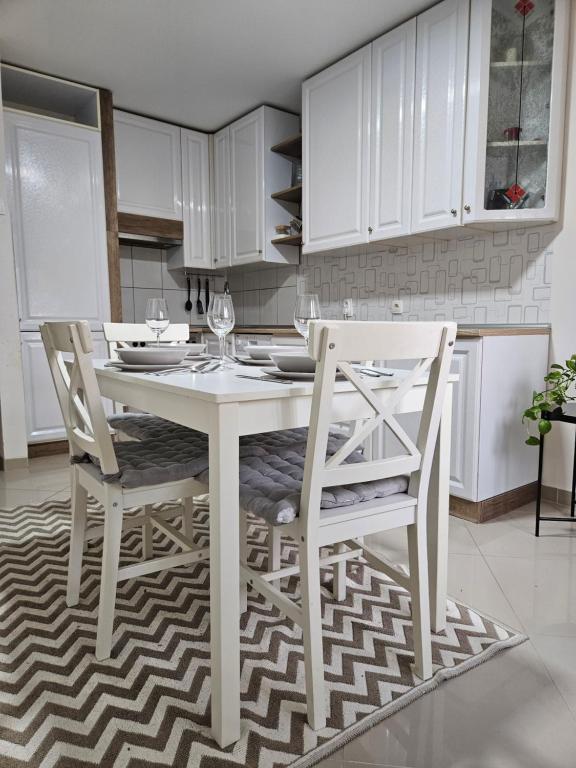 a white kitchen with a white table and chairs at Epicentar apartment in Loznica