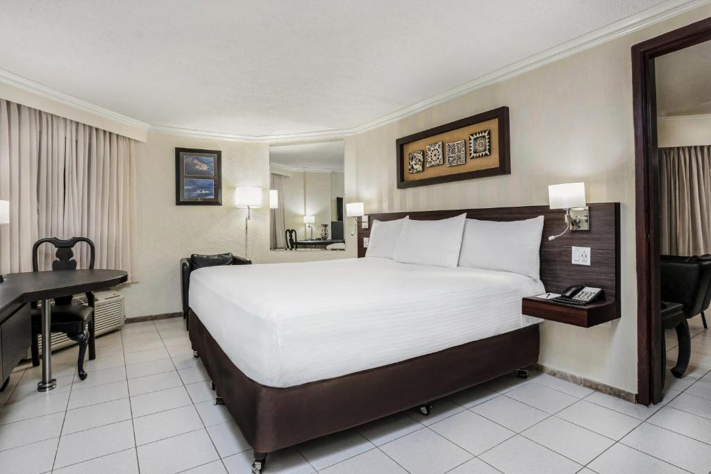a hotel room with a large bed and a desk at Copantl Hotel & Convention Center in San Pedro Sula
