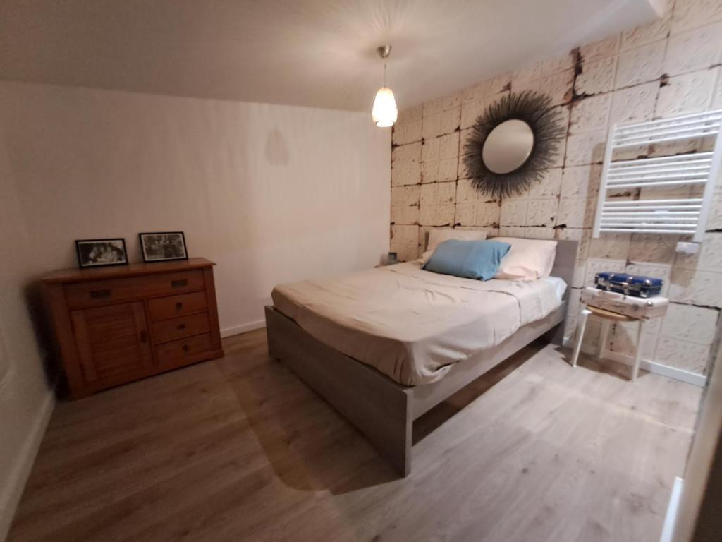 een slaapkamer met een bed en een spiegel aan de muur bij Maisonnette in Corbeil-Essonnes