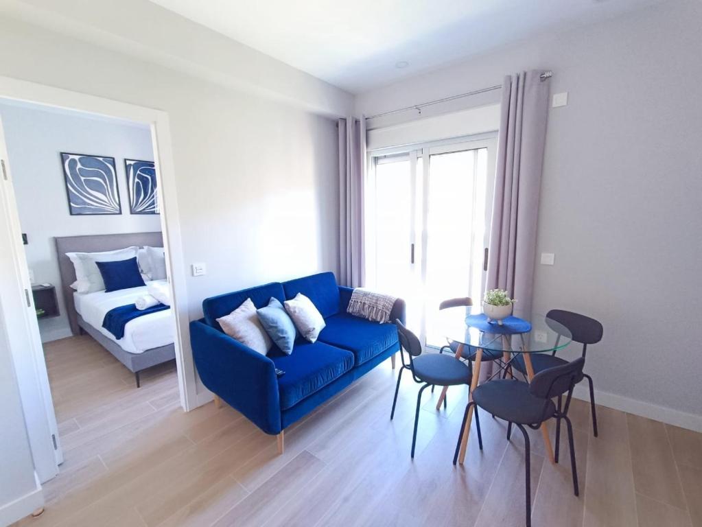 ein Wohnzimmer mit einer blauen Couch und einem Bett in der Unterkunft RAMBLA DREAMS Nuevo apartamento céntrico y 1GB in Santa Cruz de Tenerife
