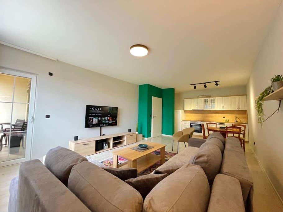 Green Downtown Apartment في فيريزاي: غرفة معيشة مع أريكة كبيرة وطاولة