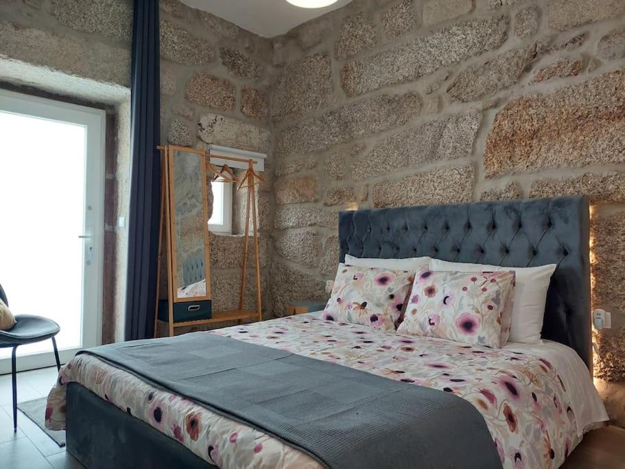 a bedroom with a bed and a stone wall at Villa Boas House in Castro Daire