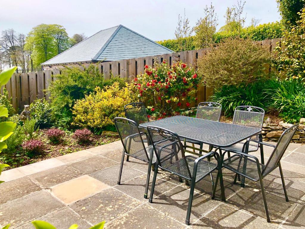 a table and chairs in a garden with a fence at Coach House in Loddiswell