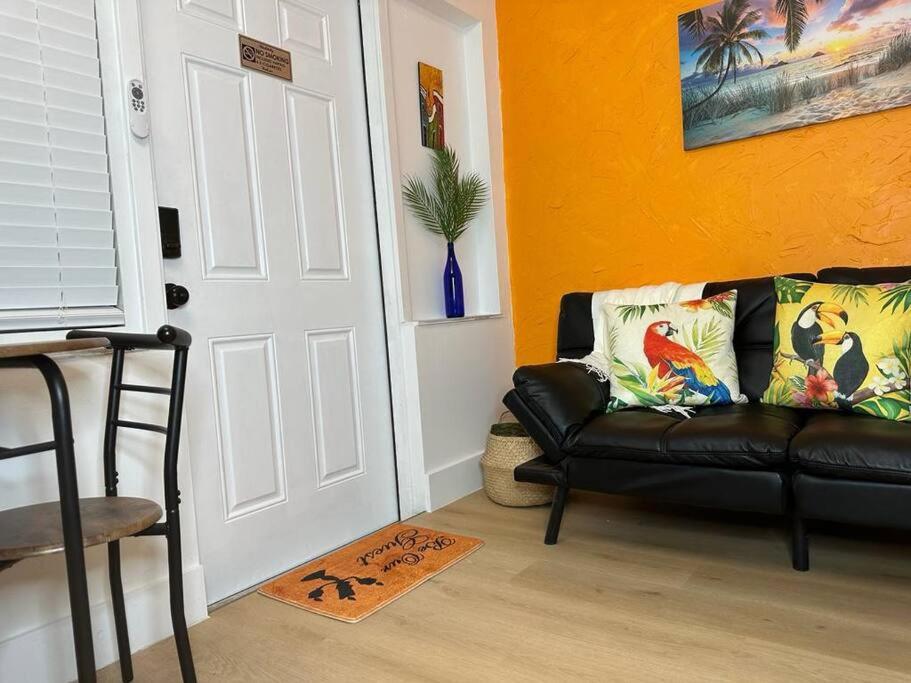 een woonkamer met een zwarte leren bank voor een deur bij Sleeps 3, Casa Tropical in Miami in Miami