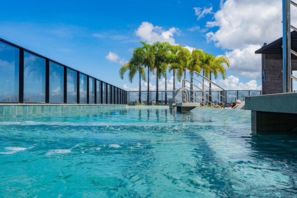 uma piscina com palmeiras num edifício em Edificio Time - 909 - Apartamento Quarto e Sala com ar condicionado, piscina, academia, jacuzzi, sauna e ampla área de lazer em Maceió