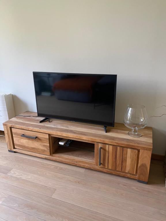 uma televisão de ecrã plano em cima de um centro de entretenimento em madeira em Room in flat 174 em Gent