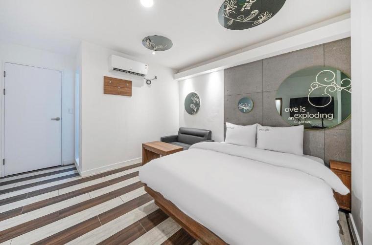 大邱的住宿－OU Hotel，卧室配有一张白色大床和一把椅子
