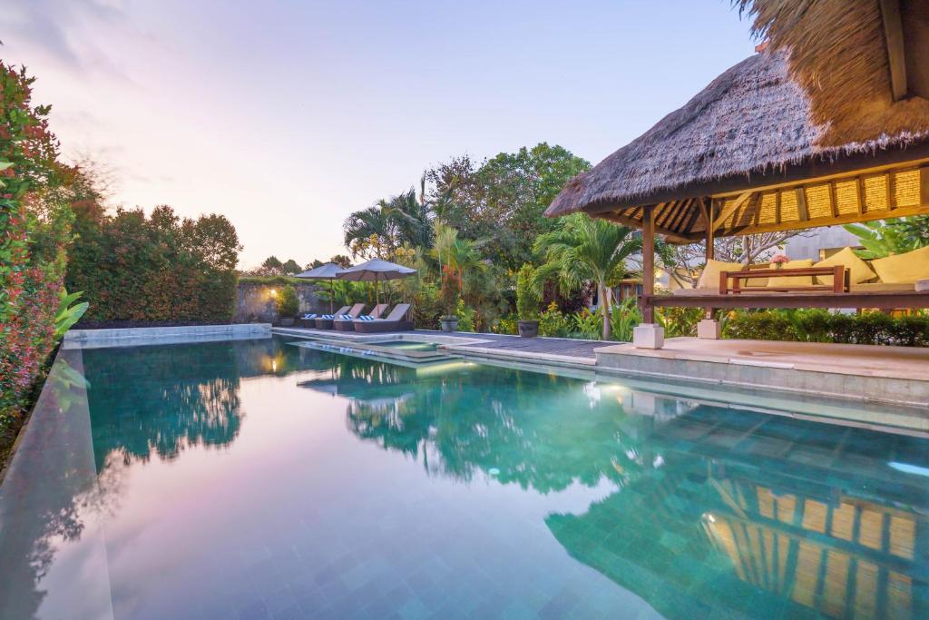 a swimming pool next to a house with a building at Villa Kaira Estate in Canggu