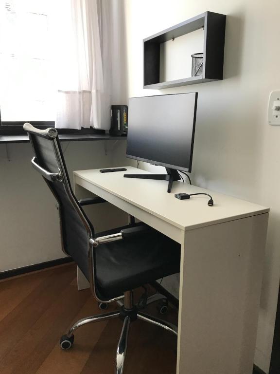 un monitor de ordenador sentado en un escritorio con una silla en Confortável, Equipado e Bem Localizado c/ Garagem, en Curitiba