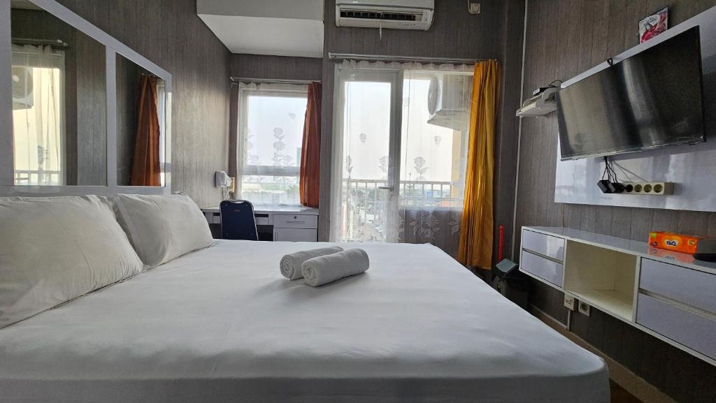 Un dormitorio con una cama con una toalla. en Studio5 at LRT Cikunir 1 next to Ibis Styles Jatibening -Min Stay 3 nights- en Kedaung Dua